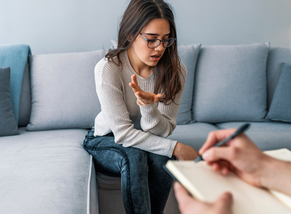 Girl speaking to counsellor whilst they take notes in session